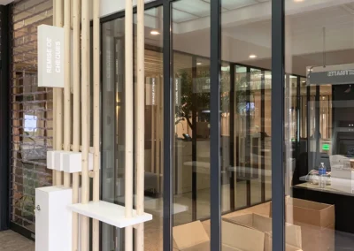 L'entrée dans la banque, entre verrière verticale et horizontale, promet un parcours architectural attrayant dans cette agence bancaire de Lorgues. On devine les perspectives, les jeux de lumière et de matériaux, la qualité des espaces et le soin apporté à l'agencement.